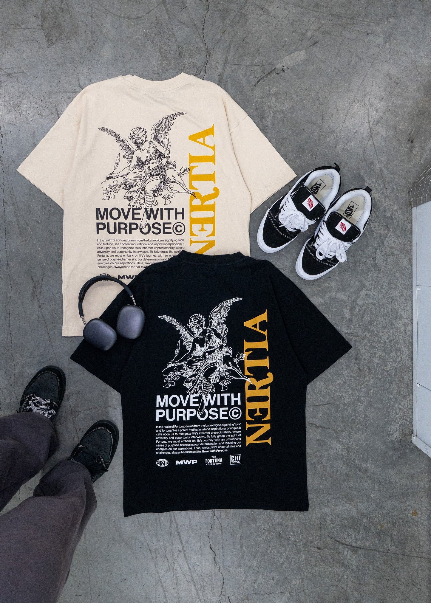 Two t-shirts, a pair of sneakers, and a backpack on a concrete floor.