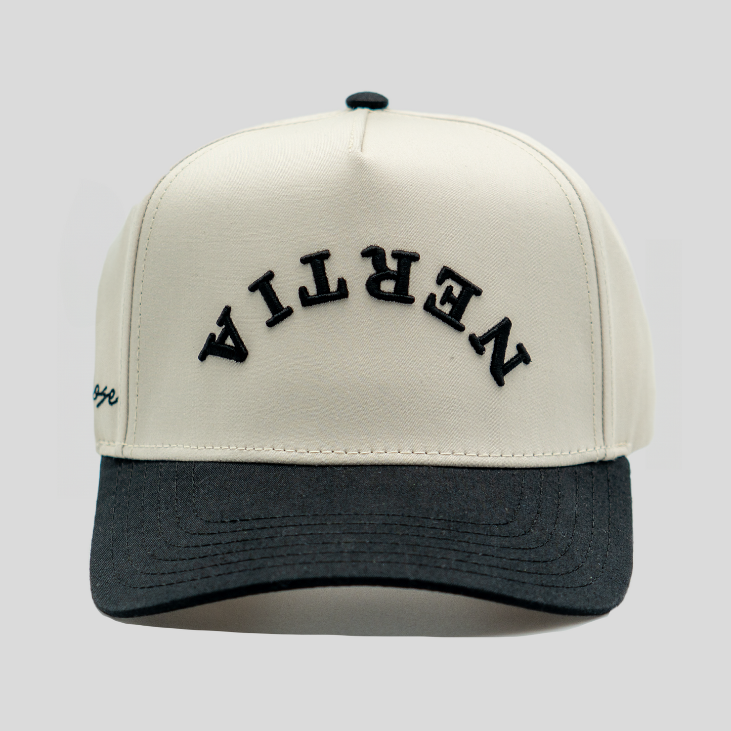 Beige and black cap with 'Nevilla' branding on a light gray background