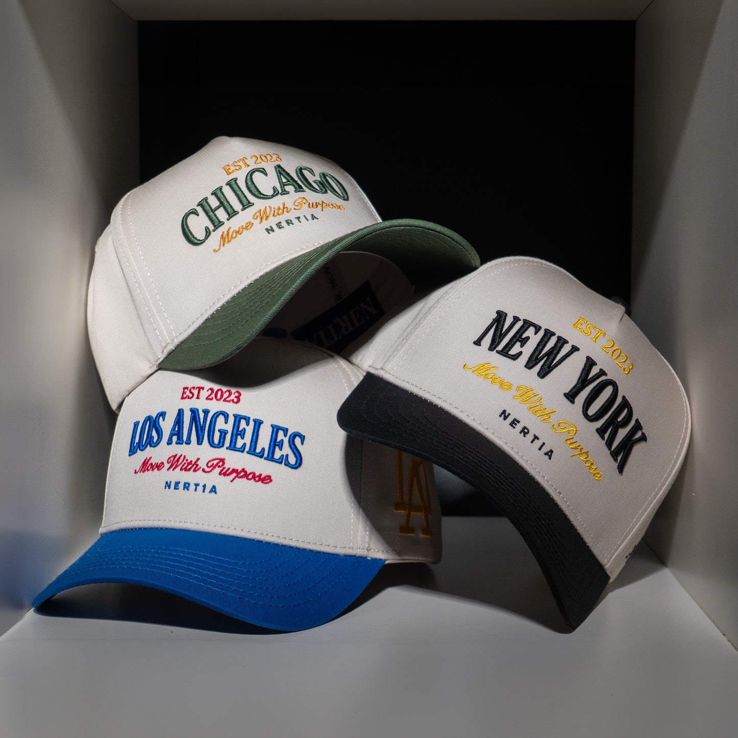 Three baseball caps with 'Chicago', 'Los Angeles', and 'New York' text on a dark background