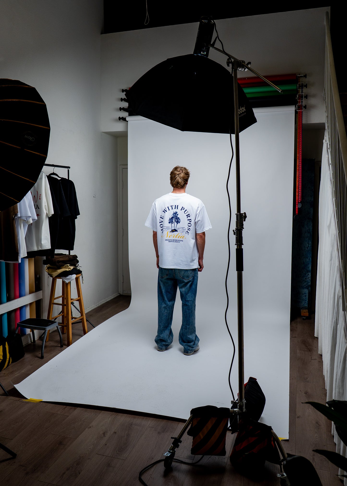 Person wearing a white t-shirt with graphics in a photo studio setting.