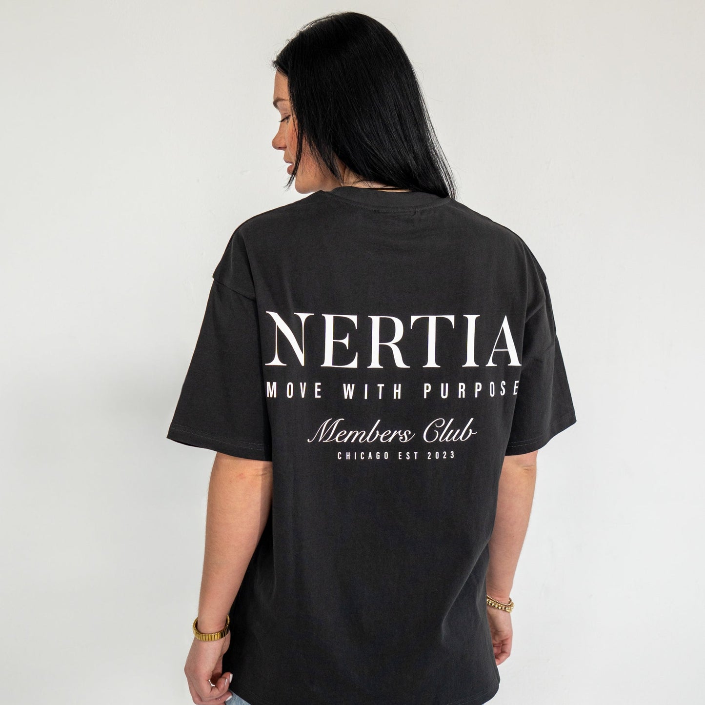 Person wearing a black t-shirt with 'Nertia' branding on the back against a plain background