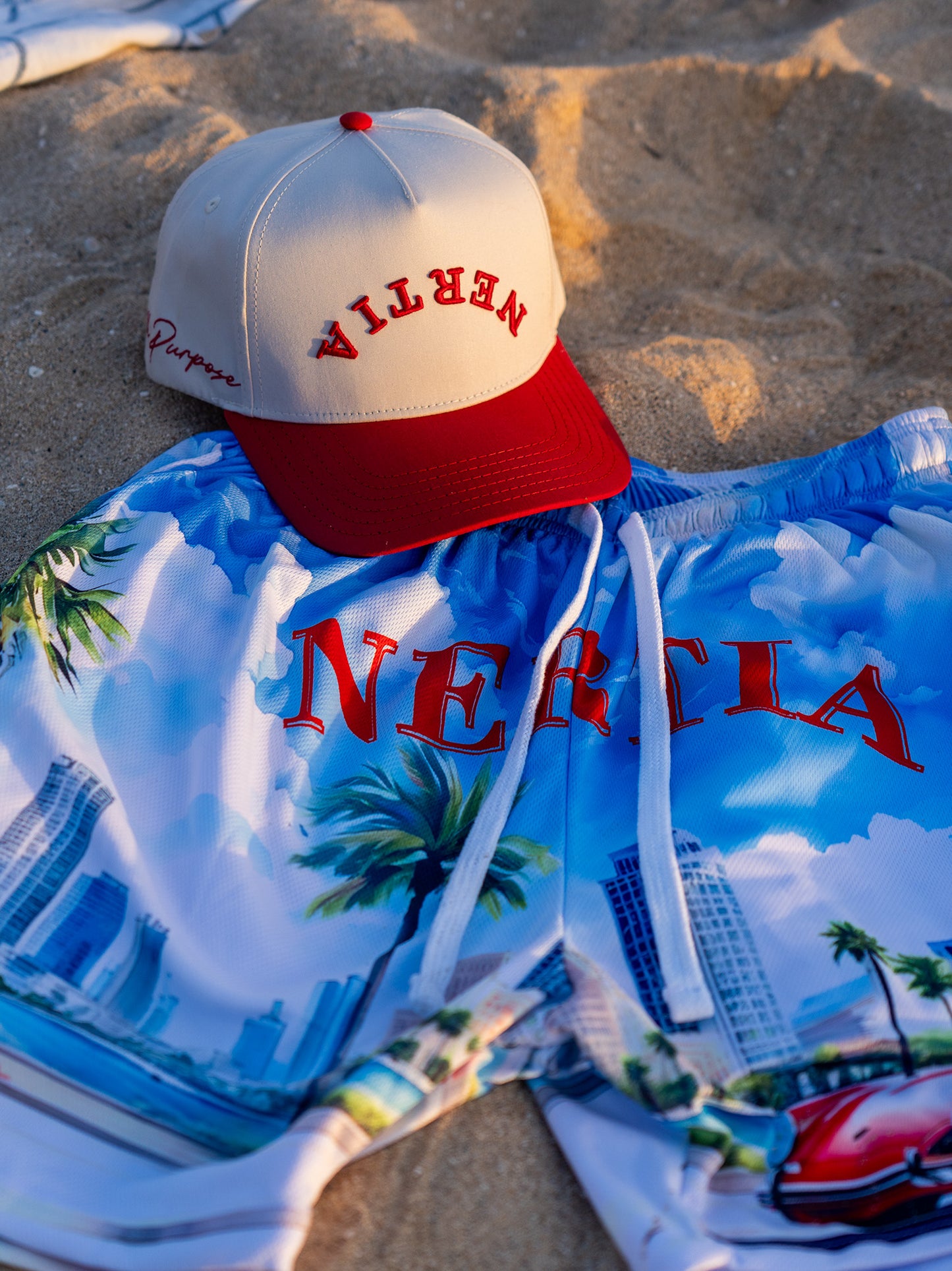 Beige and red cap on a blue and white patterned shirt with 'Nereta' text on a sandy background