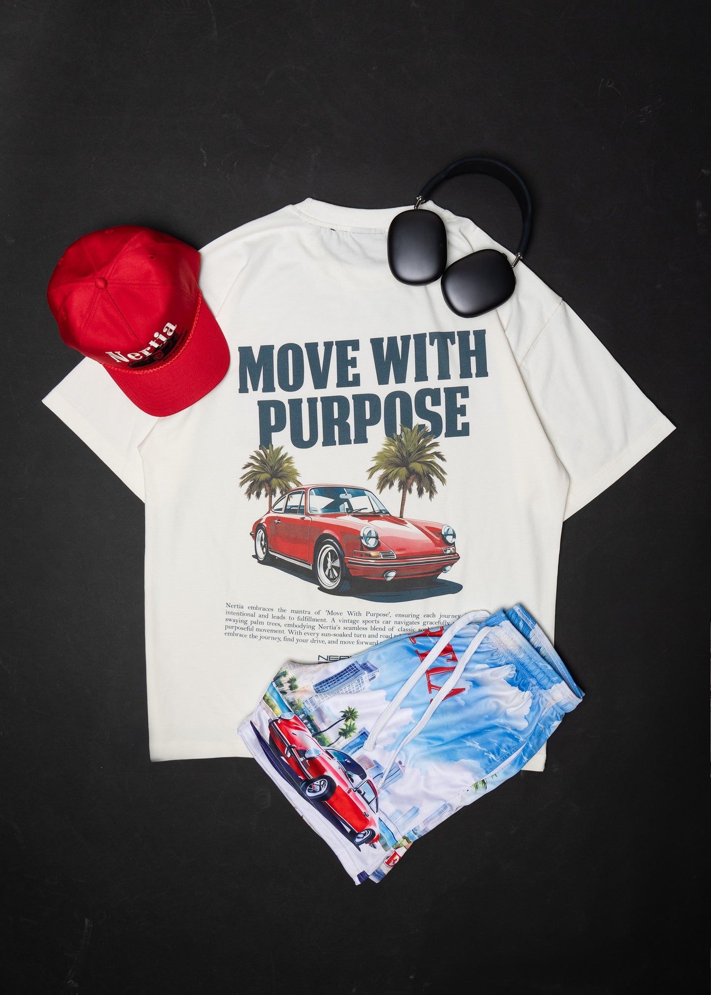 White t-shirt with car graphic and text, red cap, sunglasses, and swim shorts on a black background