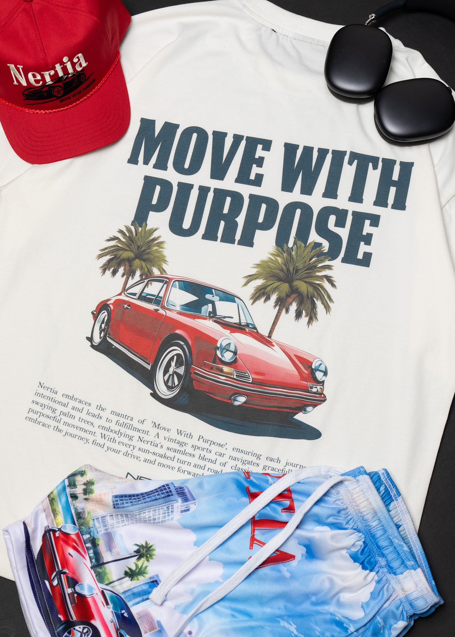 White t-shirt with red car graphic and 'Move with Purpose' text, red cap, sunglasses, and blue shorts on a black surface.