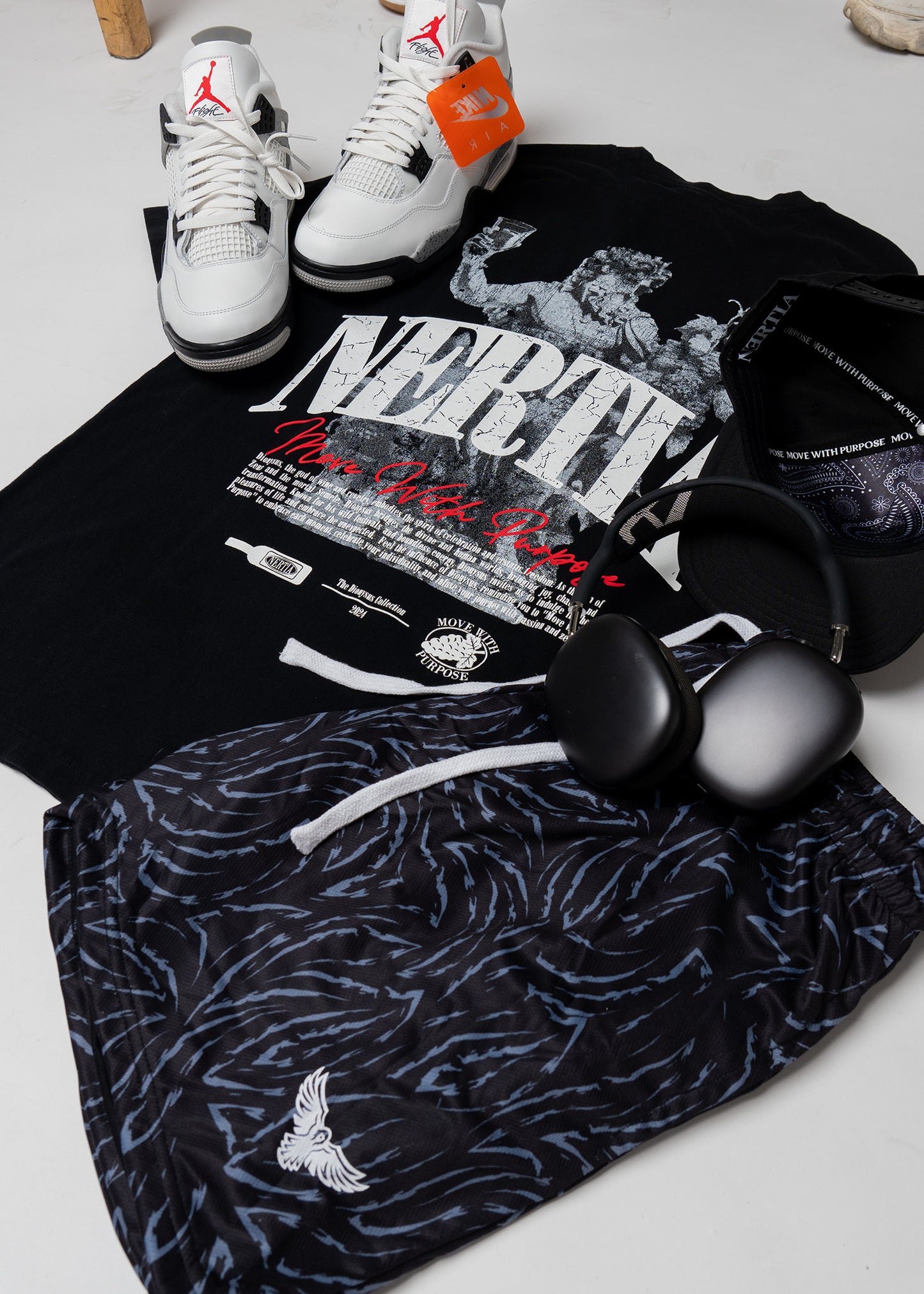 Black sweatshirt with graphic design, patterned pants, and sneakers on a light gray surface