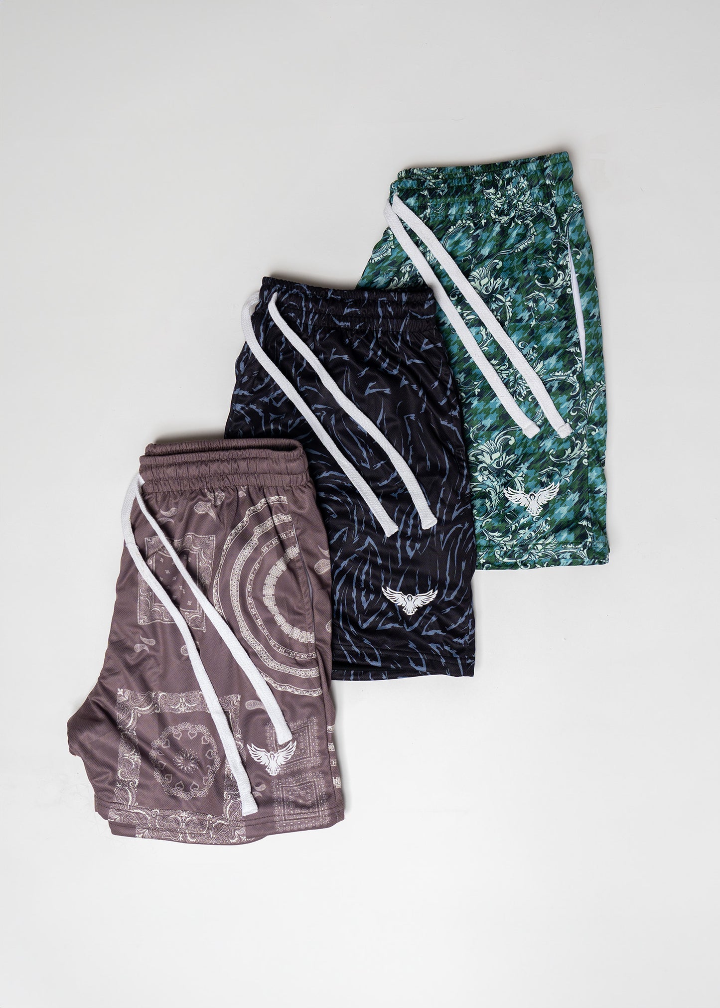 Three pairs of patterned shorts stacked on a light gray background