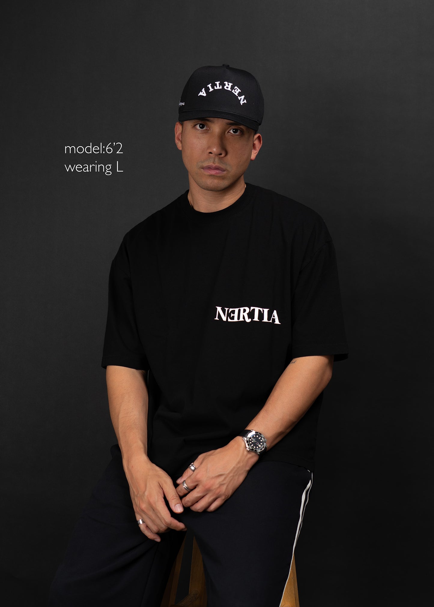 Person wearing a black t-shirt with 'NERTIA' logo and a cap on a dark background