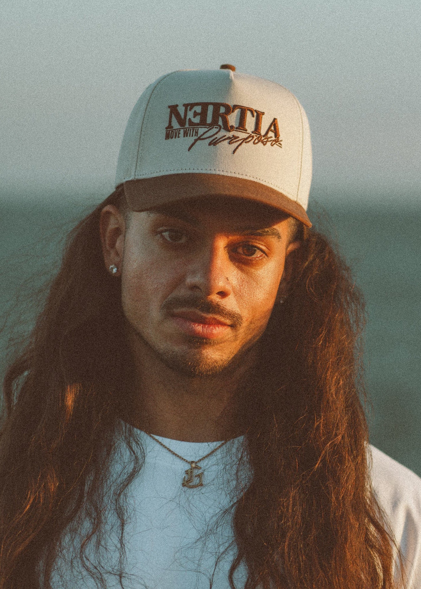 Person wearing a cap with 'Nertia' branding against a blurred natural background