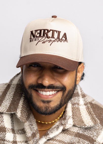 Man wearing a beige cap with text, smiling against a plain background