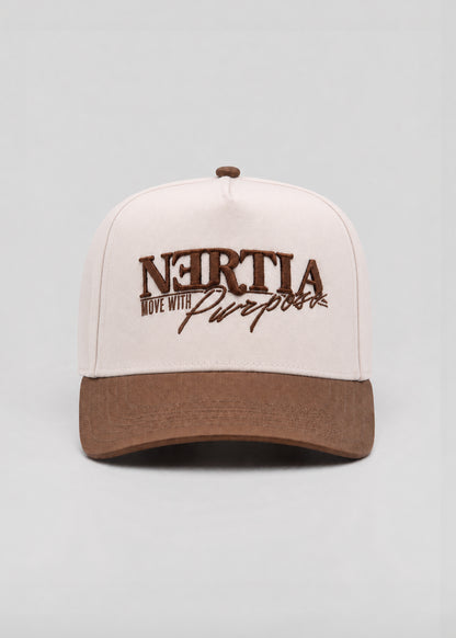 A structured baseball cap with a cream-colored crown and a brown curved brim, featuring 'NERTIA Move With Purpose' embroidered in brown on the front.