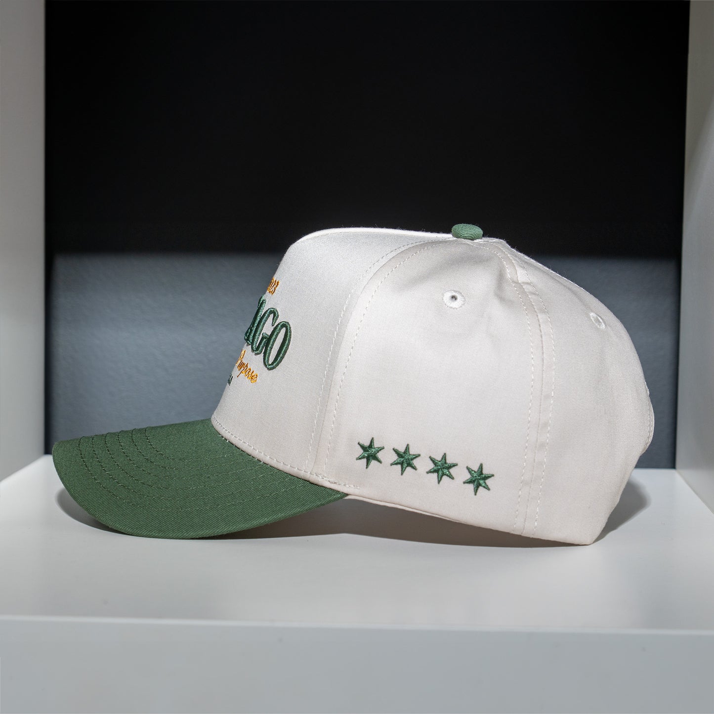 White cap with green brim and embroidered details on a gray surface