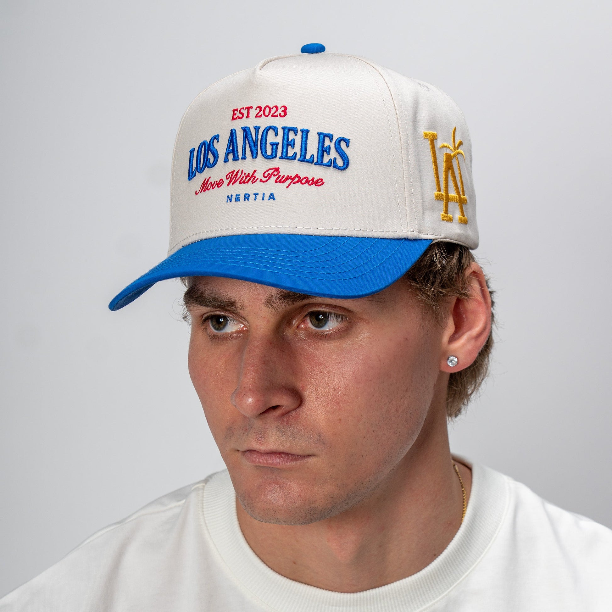 Man wearing a white and blue cap with 'Los Angeles' text on a gray background