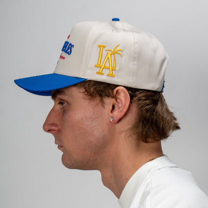 Person wearing a white cap with blue and yellow accents on a plain background