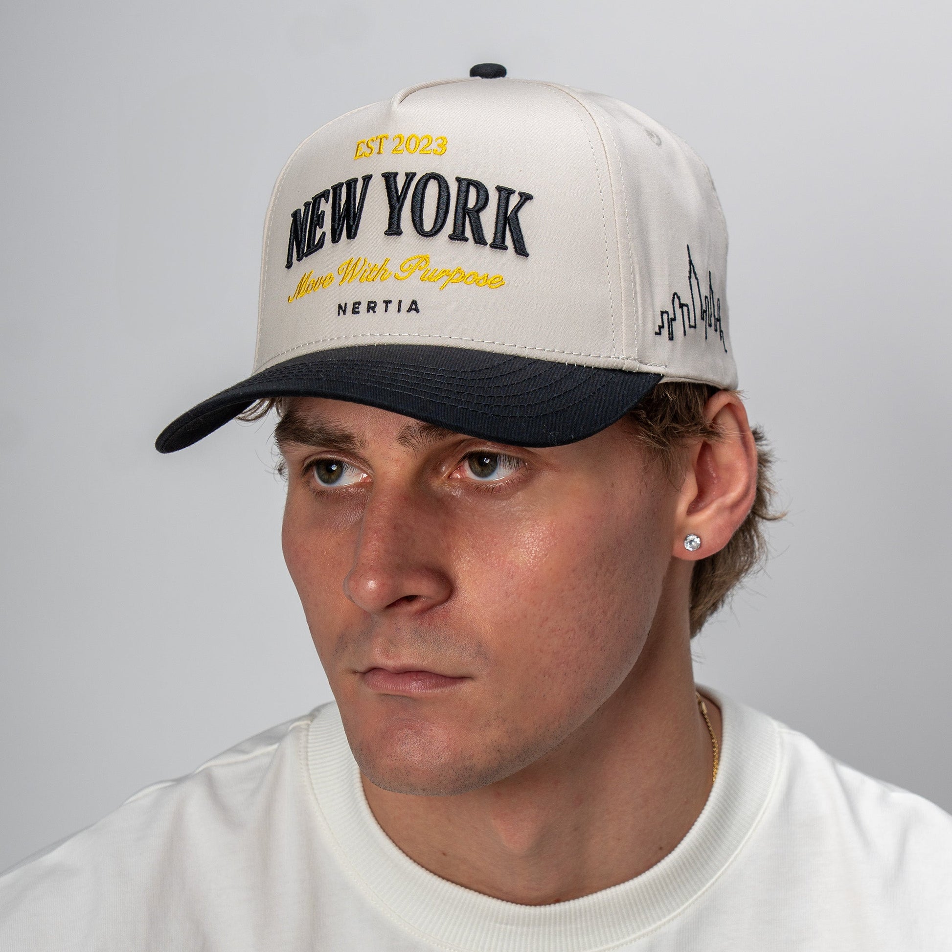 Man wearing a white cap with 'New York' text against a gray background