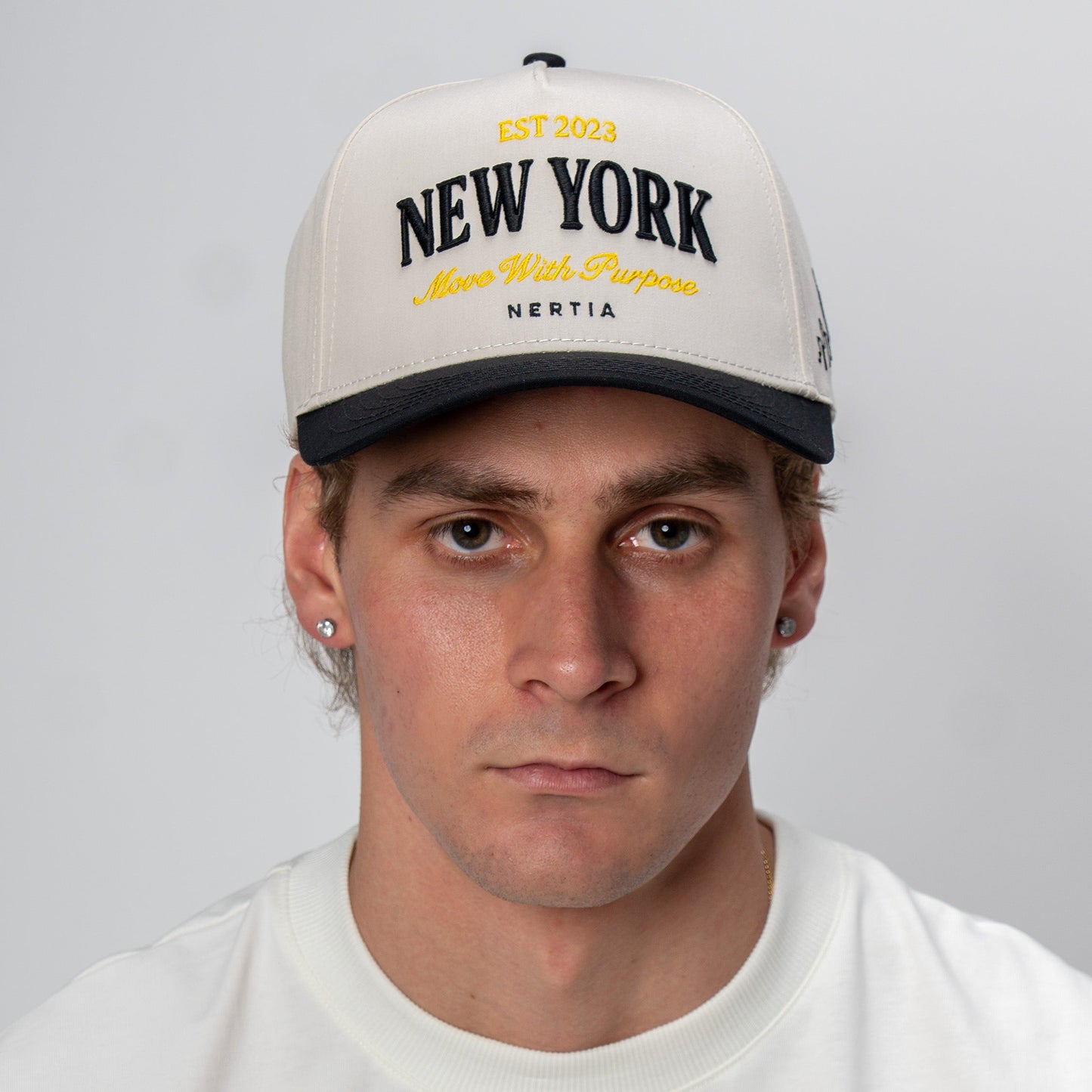 Man wearing a cap with 'New York' text on a plain background