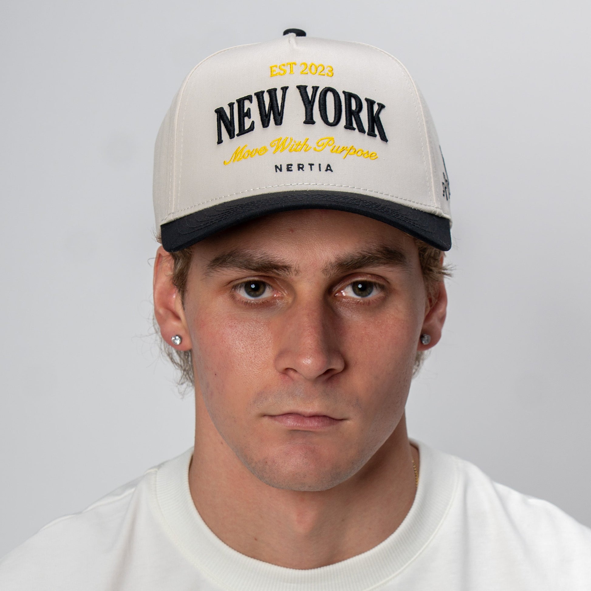 Man wearing a cap with 'New York' text on a plain background