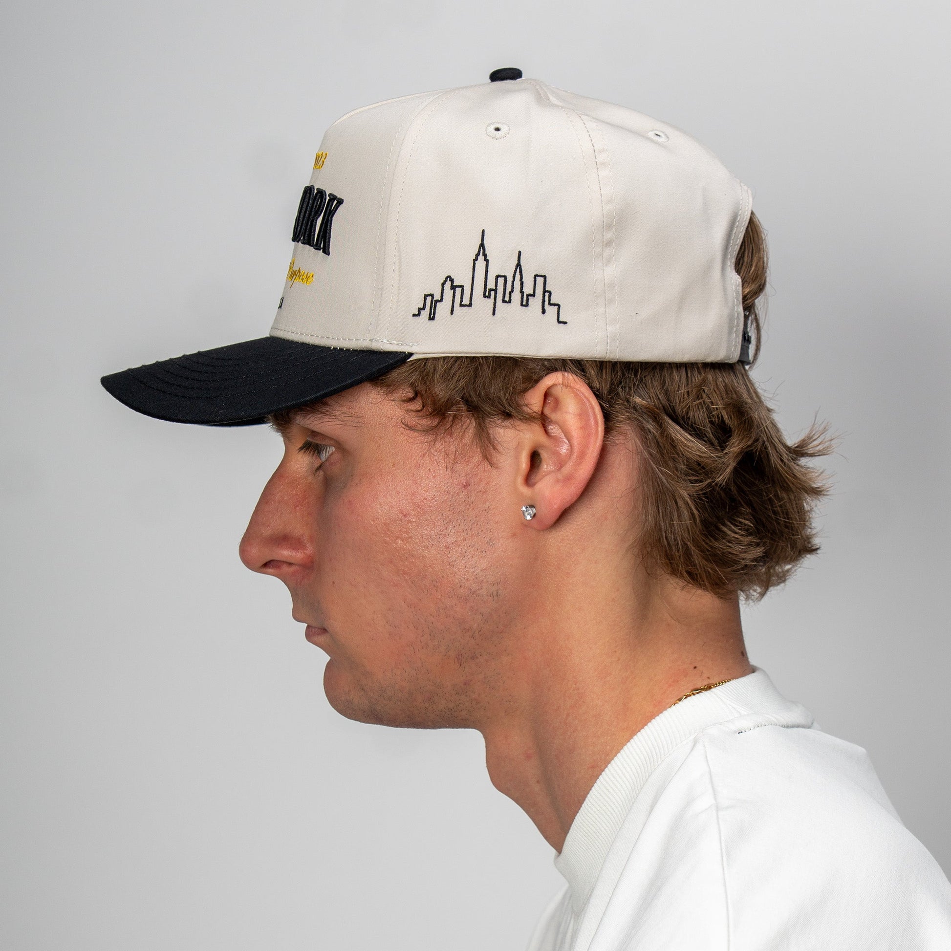 Person wearing a cap with a cityscape design on a plain background