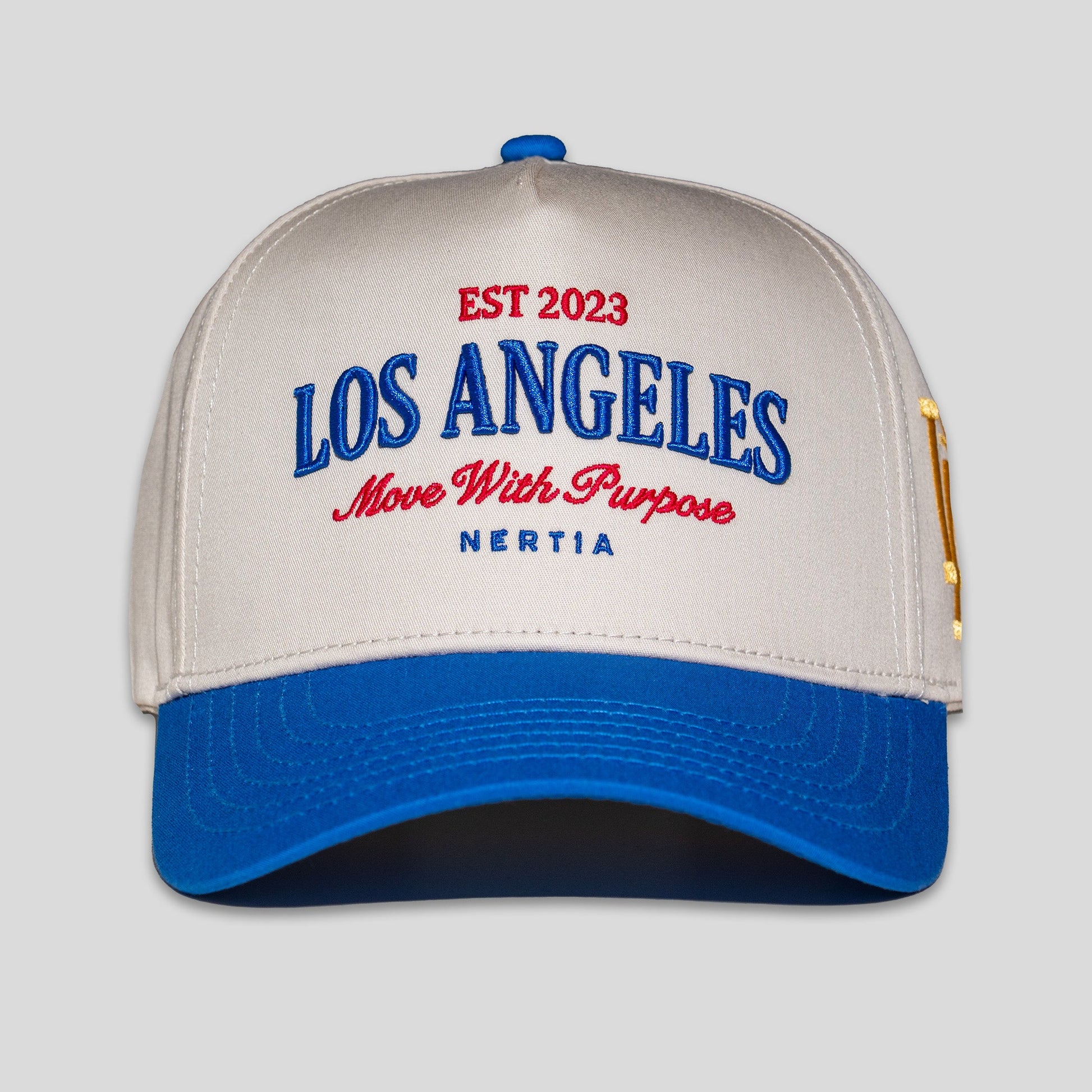 Beige and blue cap with 'Los Angeles' and 'Nertia' text on a light gray background
