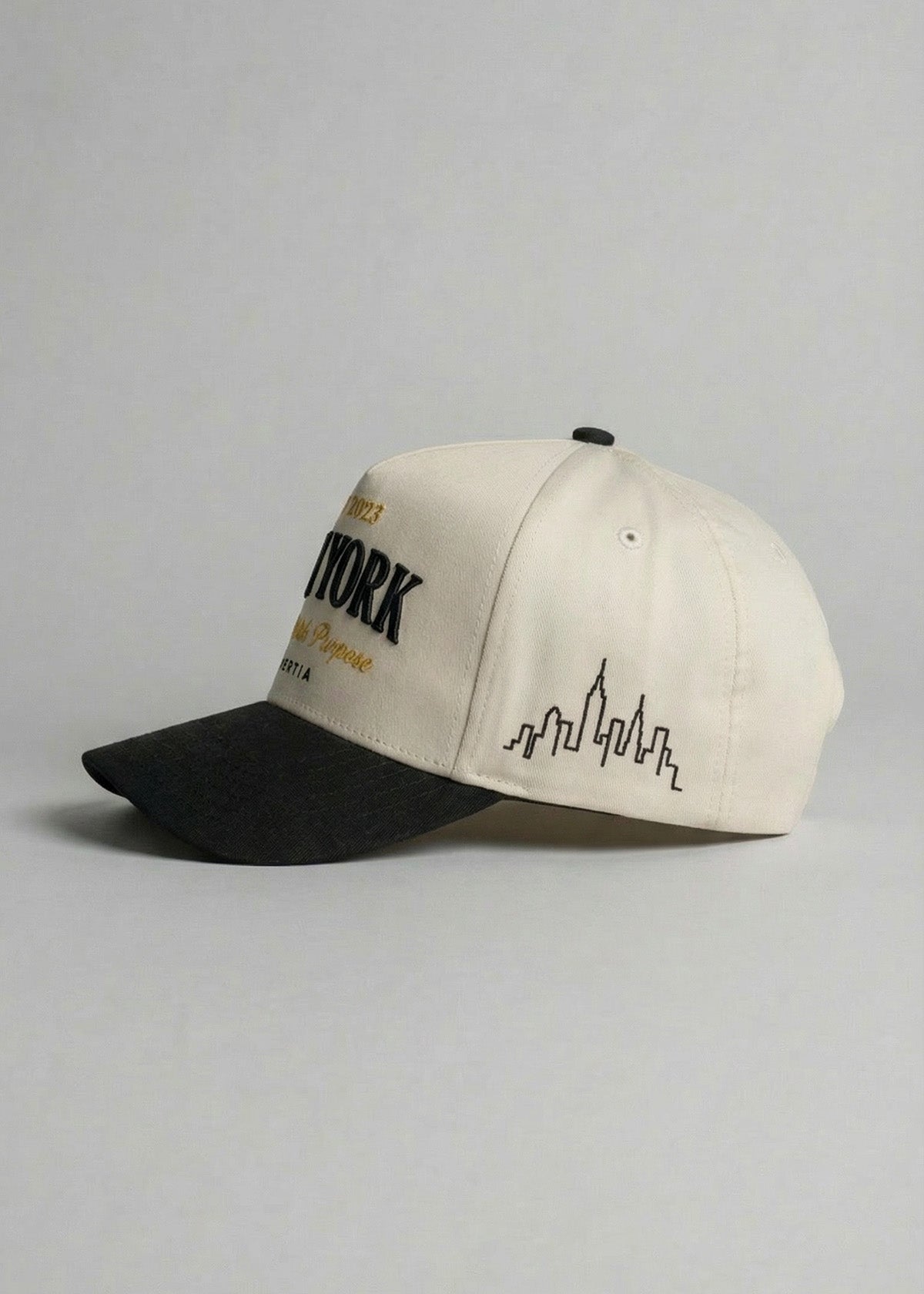 Beige and black cap with city skyline design on a gray background