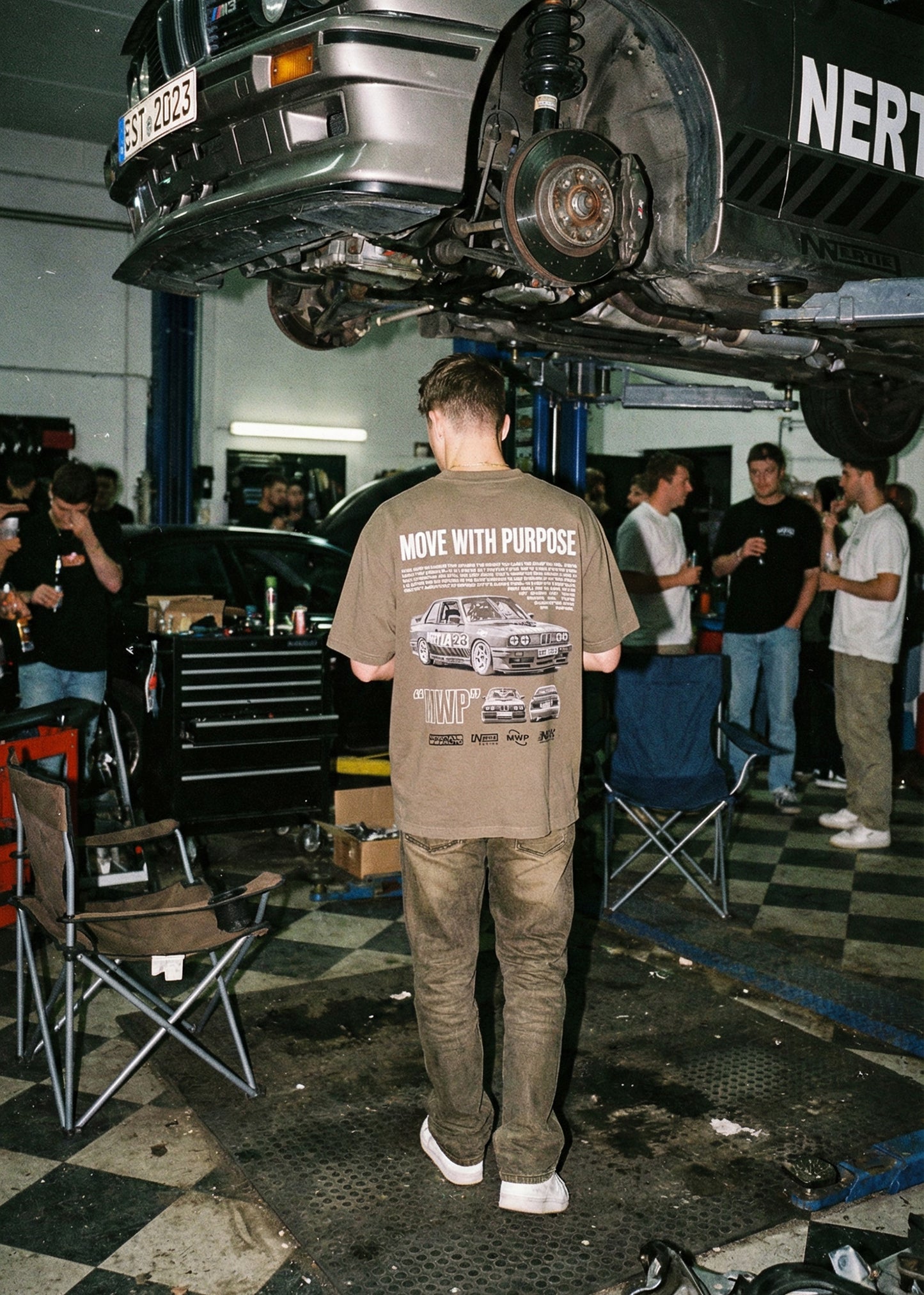 Person wearing a t-shirt with car graphics in a garage setting