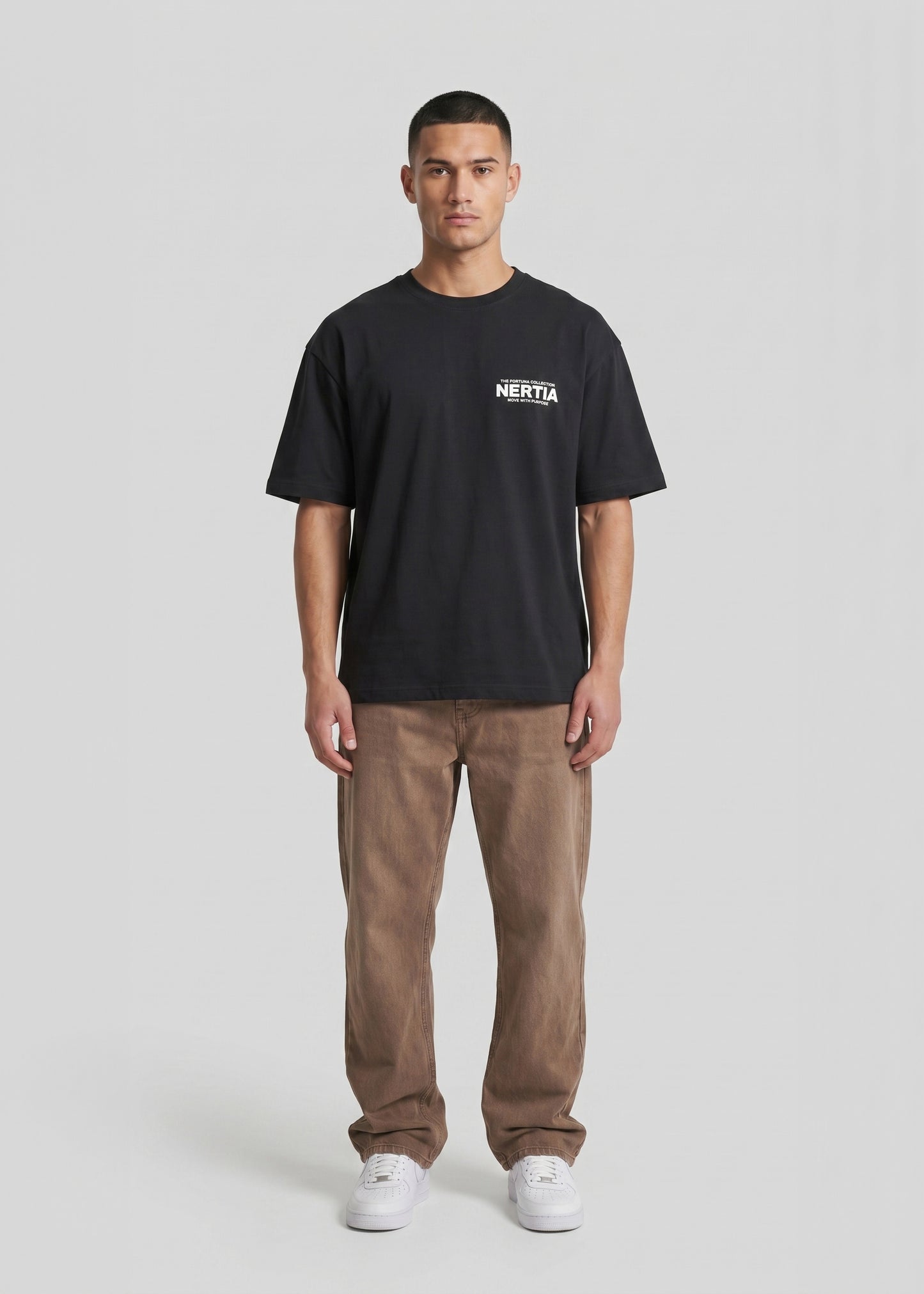 Person wearing a black t-shirt with a logo and brown pants on a white background