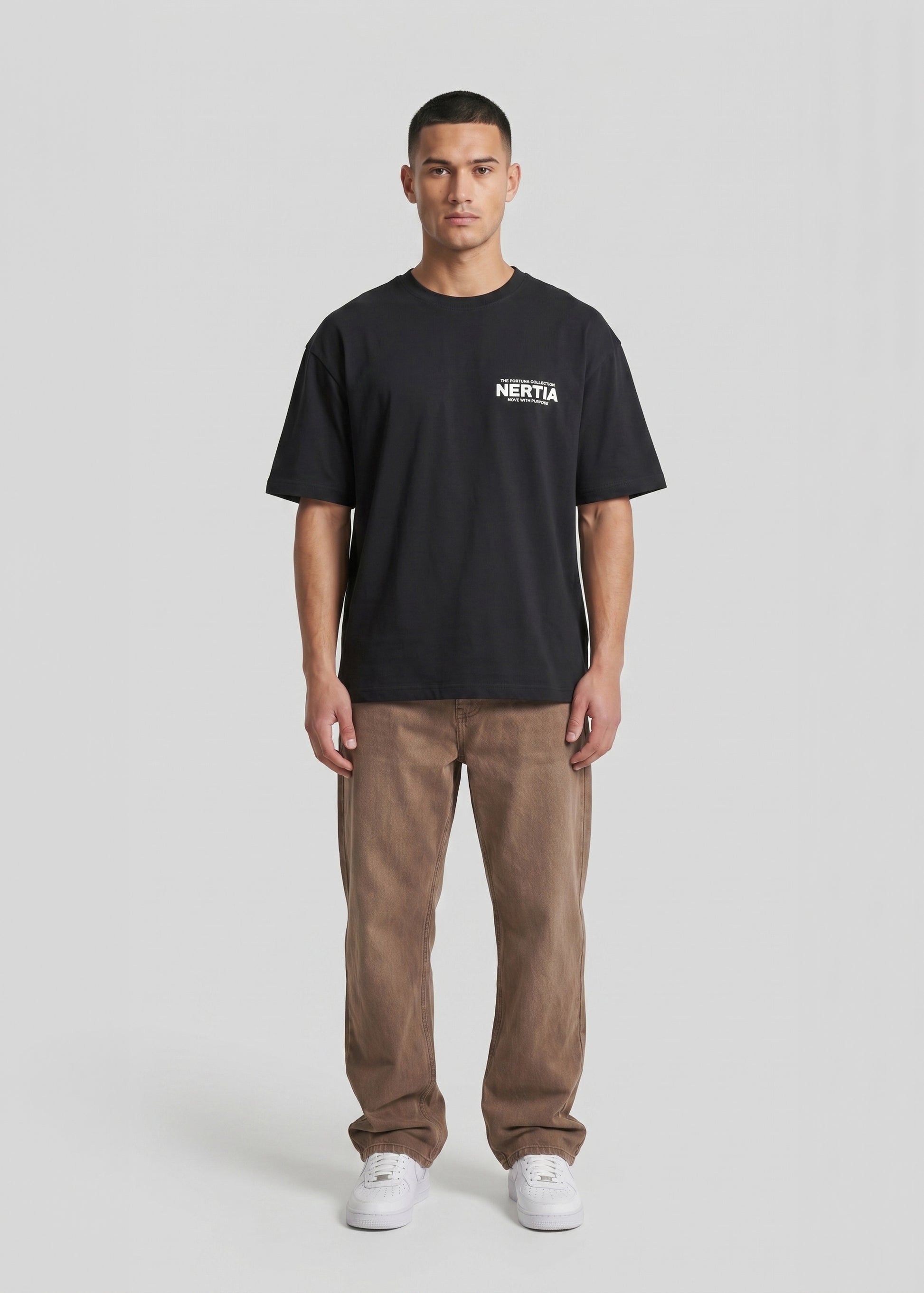 Person wearing a black t-shirt with a logo and brown pants on a white background