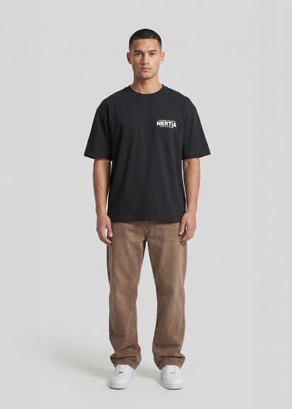 Person wearing a black t-shirt with a logo and brown pants on a white background