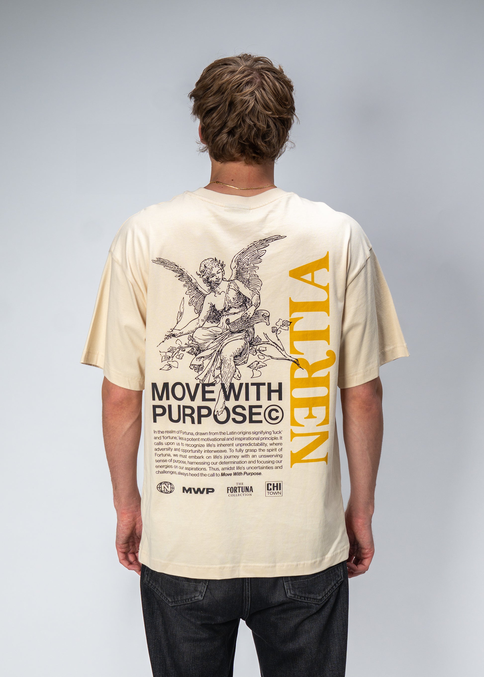 Person wearing a beige t-shirt with graphics and text on the back, standing against a plain background