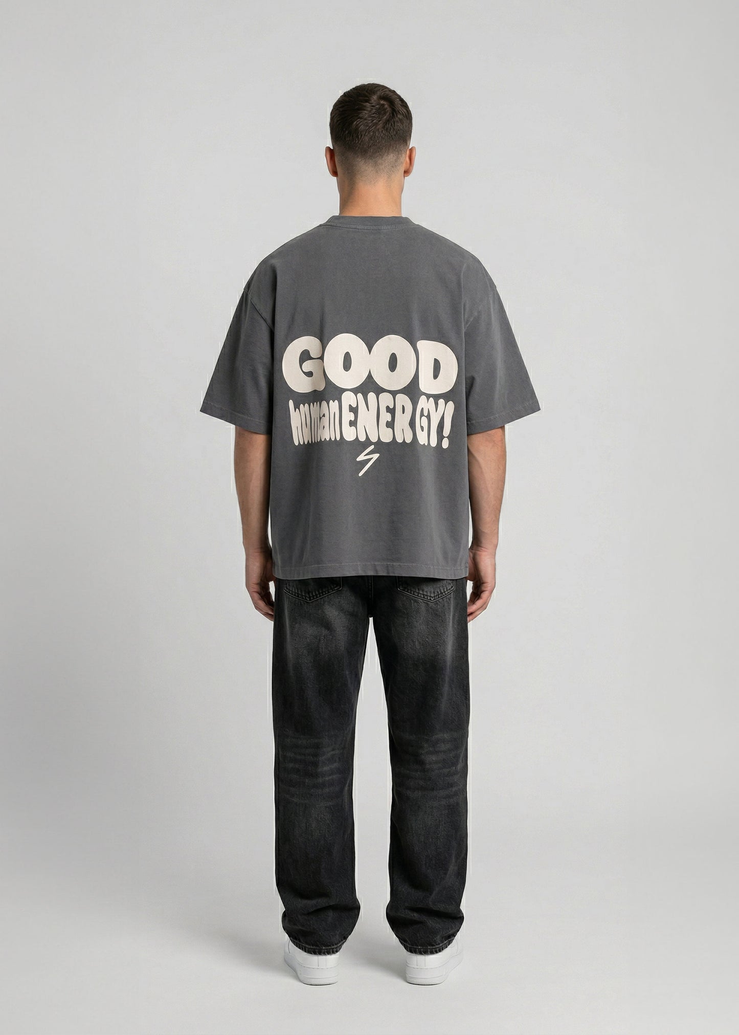 Person wearing a gray t-shirt with 'Good Vibes' text on the back, standing against a plain background