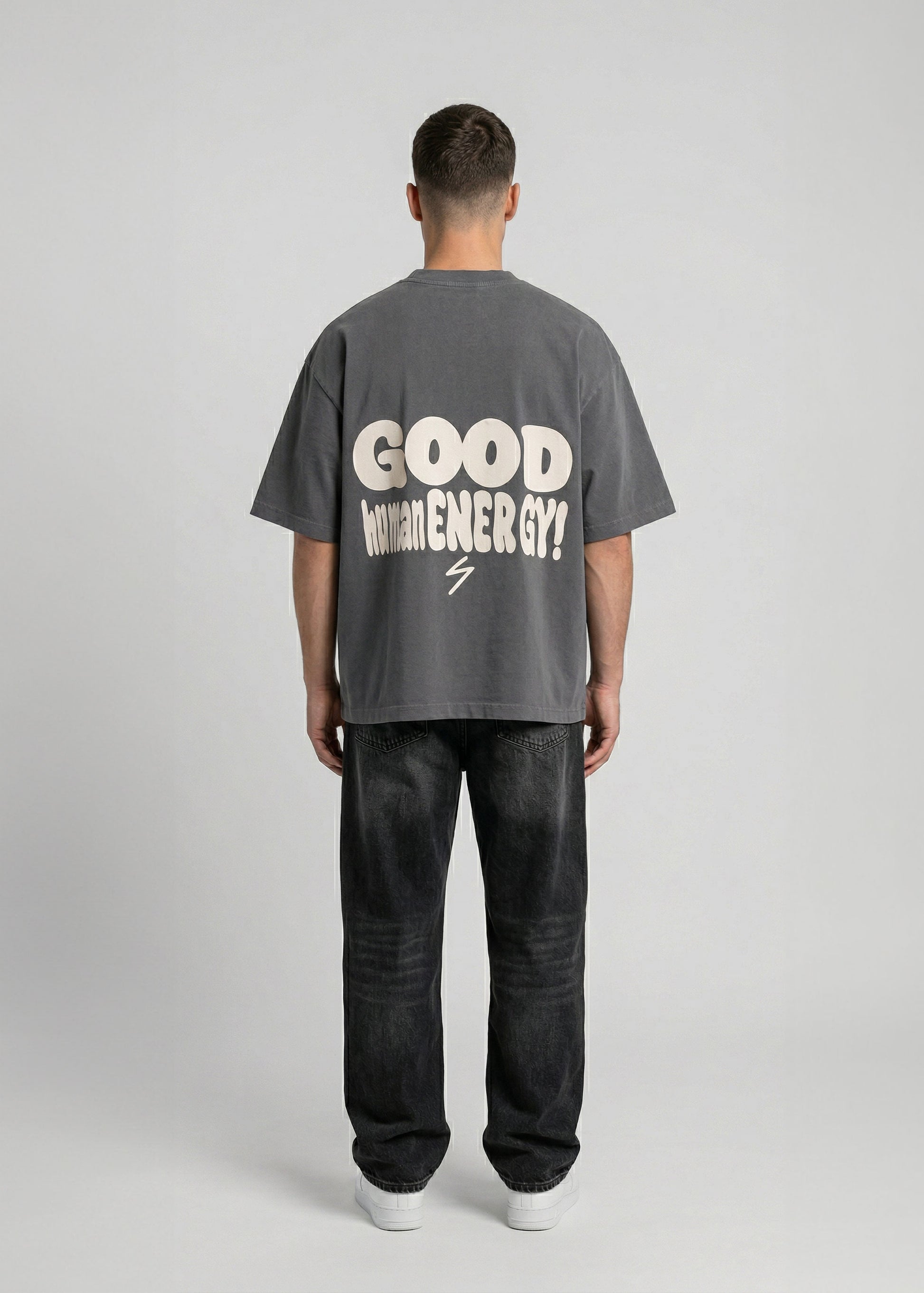 Person wearing a gray t-shirt with 'Good Vibes' text on the back, standing against a plain background