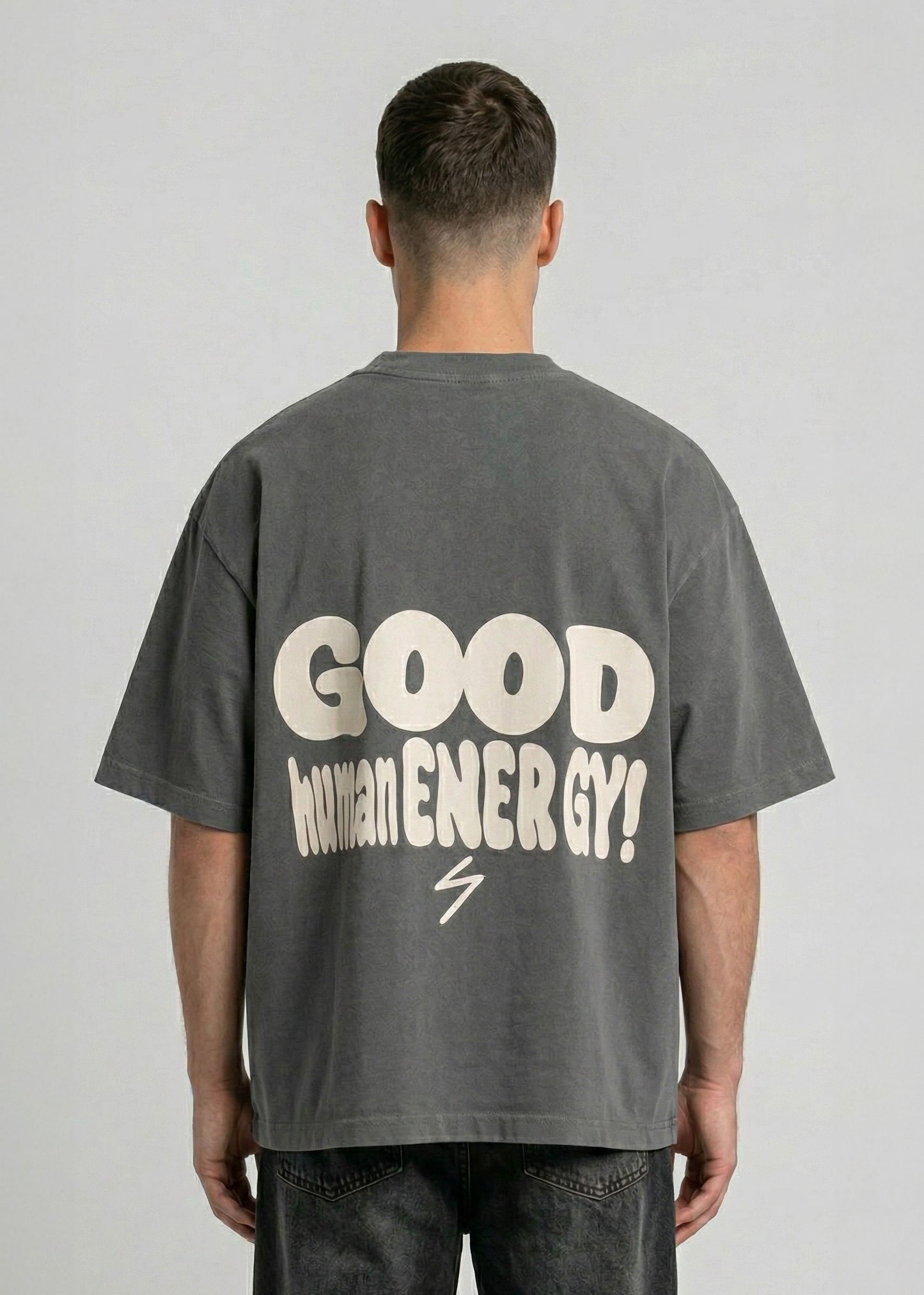 Person wearing a gray t-shirt with 'GOOD WOMAN ENERGY!' text on the back against a plain background