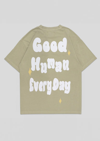 Beige t-shirt with 'Good Human Every Day' text on a light gray background