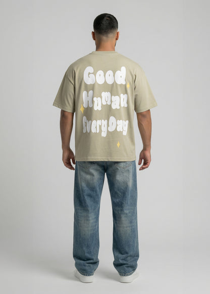 Person wearing a beige t-shirt with text and blue jeans on a plain background