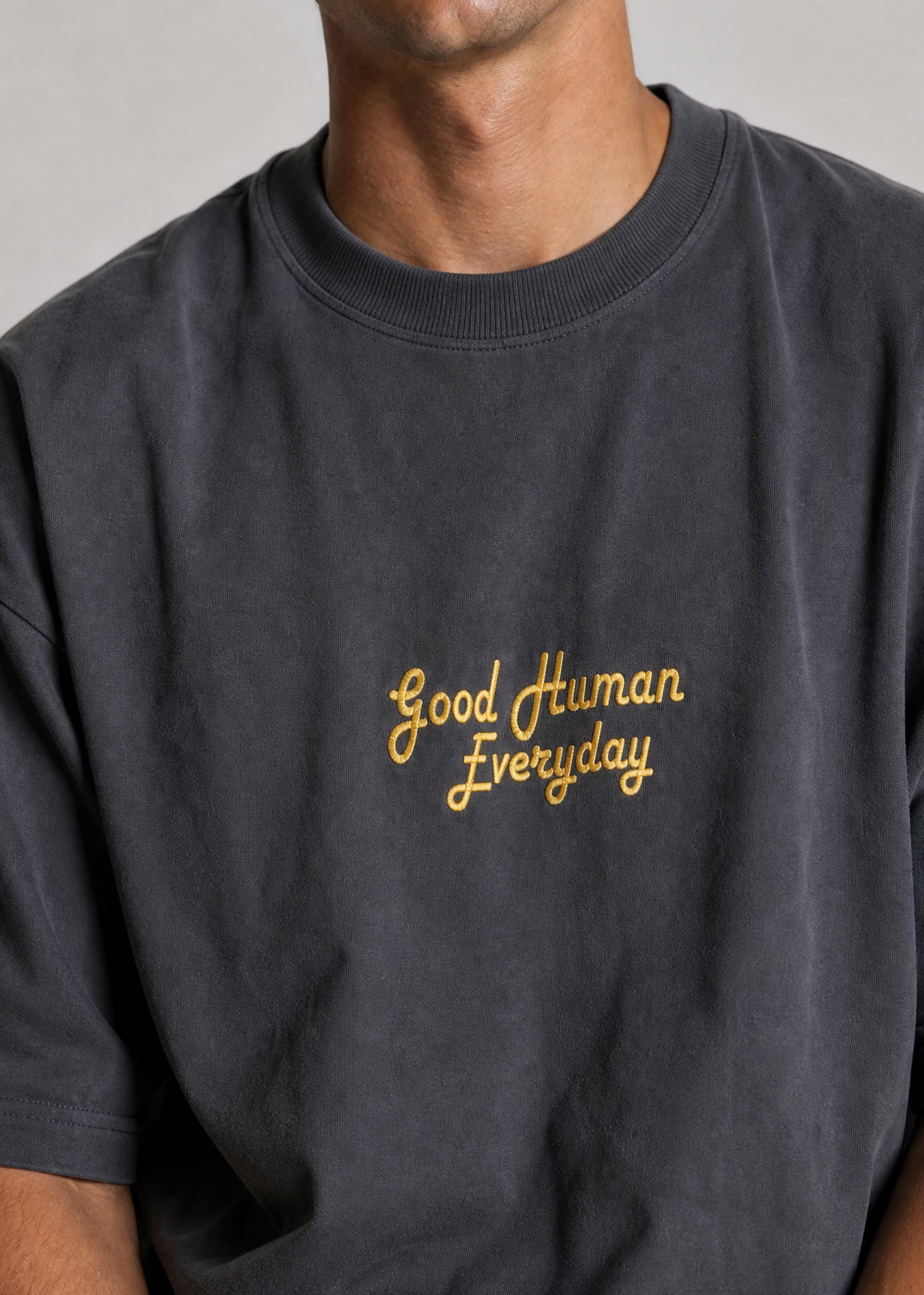 Person wearing a black t-shirt with 'Good Human Everyday' text in gold on a plain background