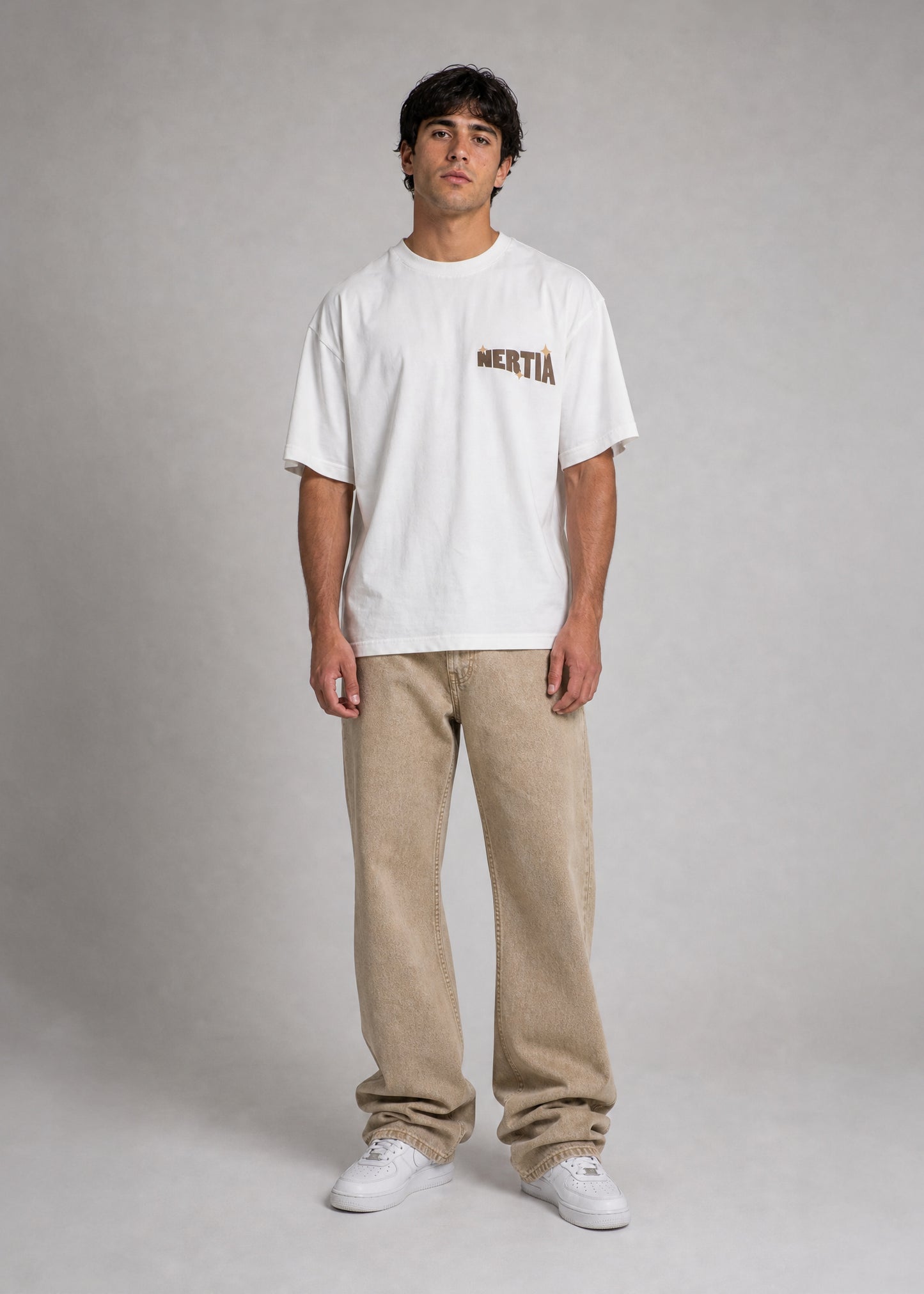 Person wearing a white t-shirt with text and beige pants on a gray background