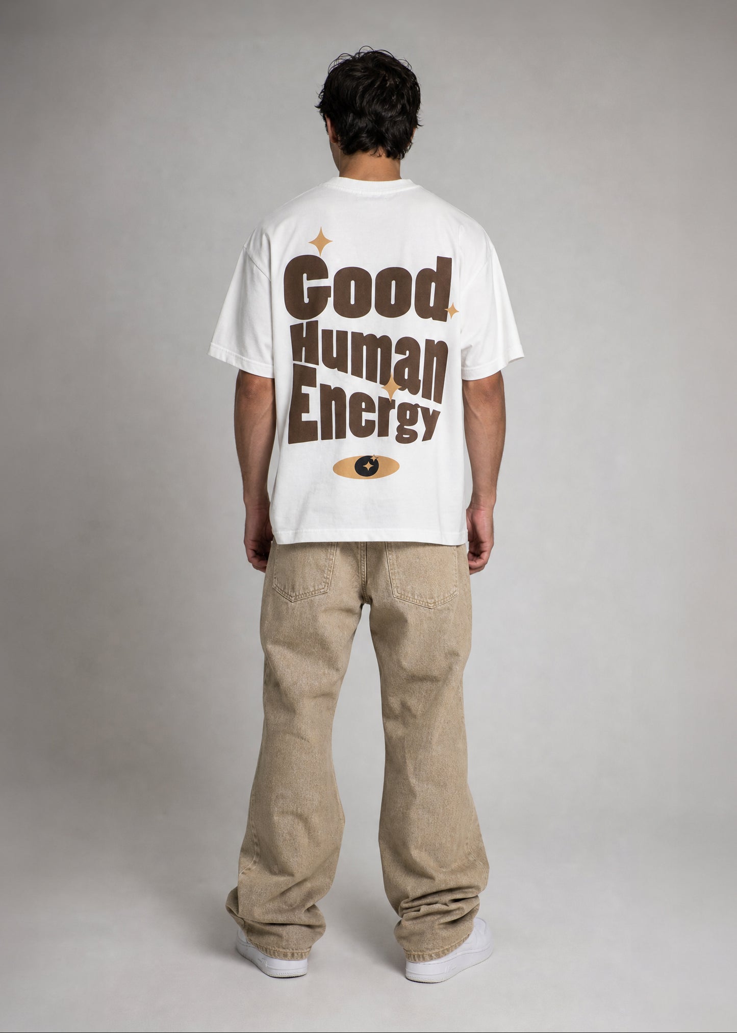 Person wearing a white t-shirt with 'Good Human Energy' text on the back, standing against a plain background.