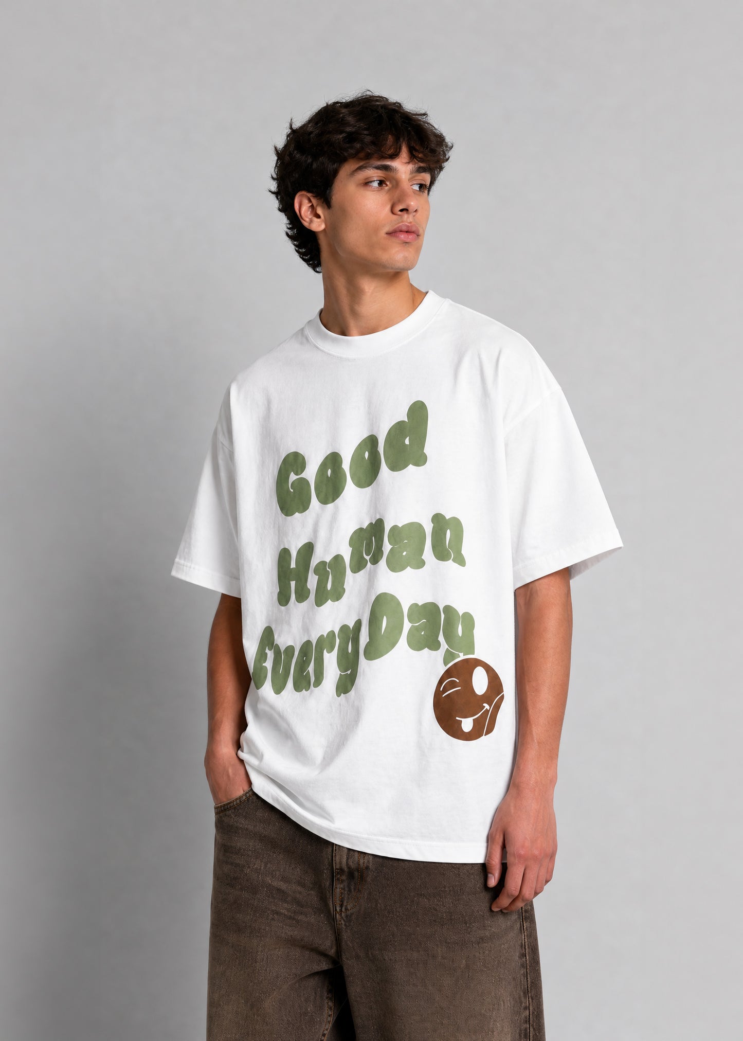Person wearing a white t-shirt with green text and a logo on a gray background