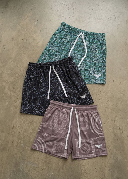 Three pairs of patterned shorts on a concrete surface