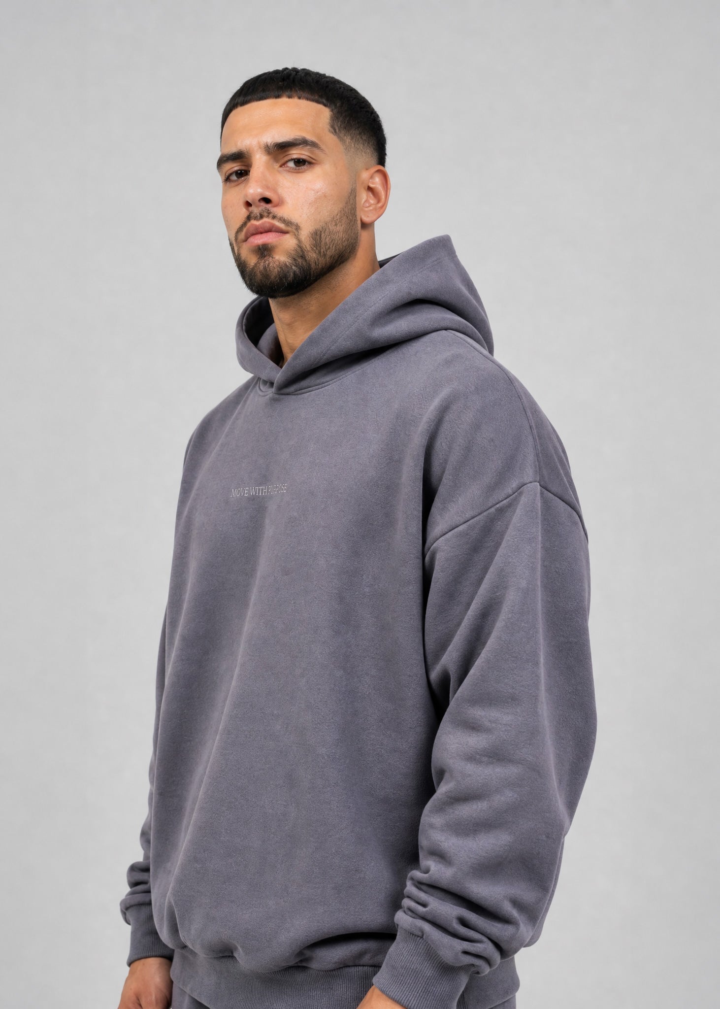 Man wearing a gray hoodie with a brand logo on a plain background