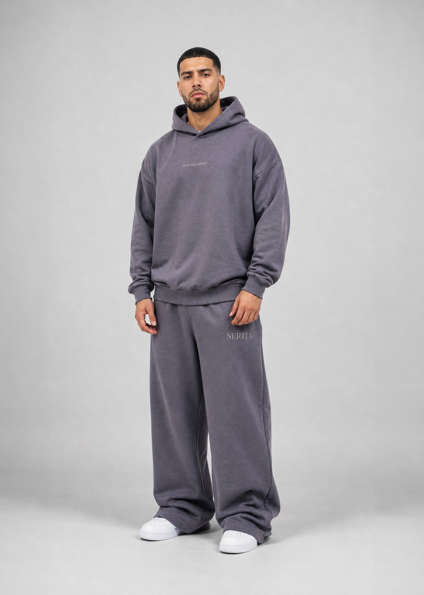 Man wearing a gray tracksuit with brand logo on a plain background