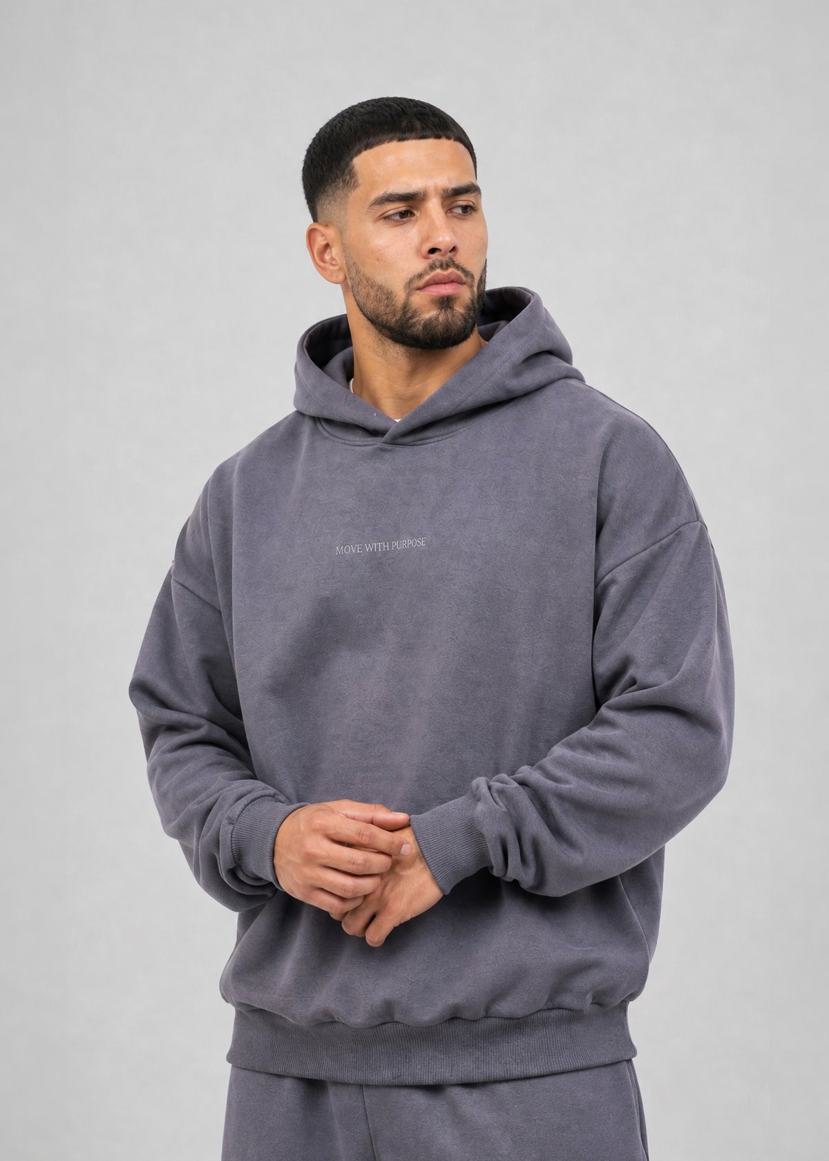 Man wearing a gray hoodie with a brand logo on a light gray background