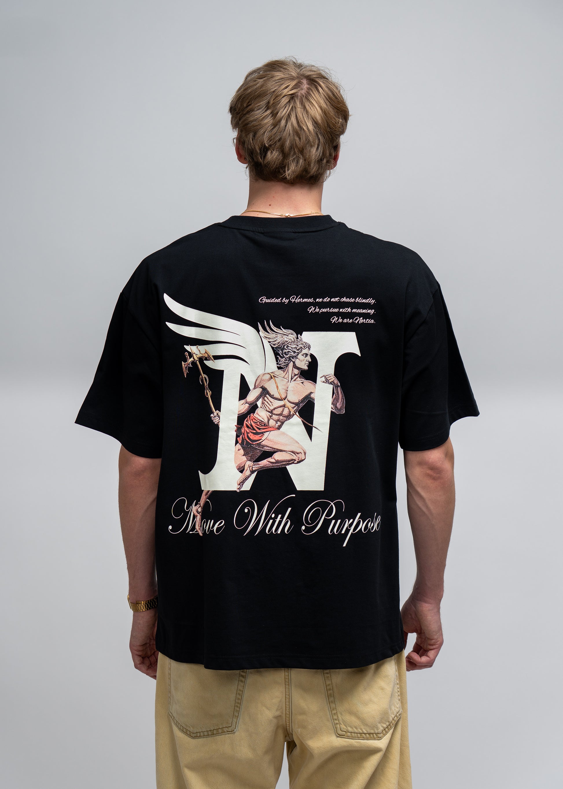 Person wearing a black t-shirt with a graphic design on the back, standing against a plain background.