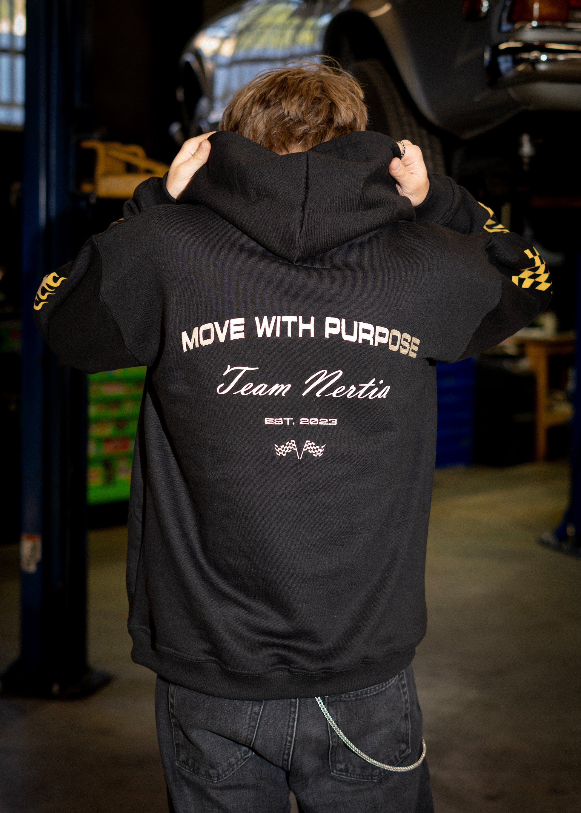 Person wearing a black hoodie with text in a garage setting