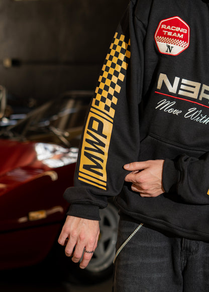 Person wearing a black hoodie with racing-themed designs and text, sitting next to a car.