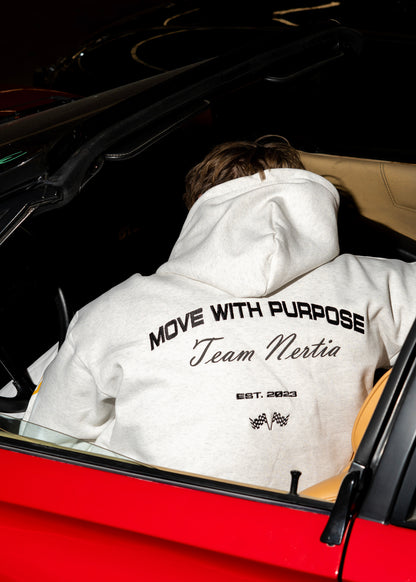 Person wearing a white hoodie with text in a car, sitting in the driver's seat.