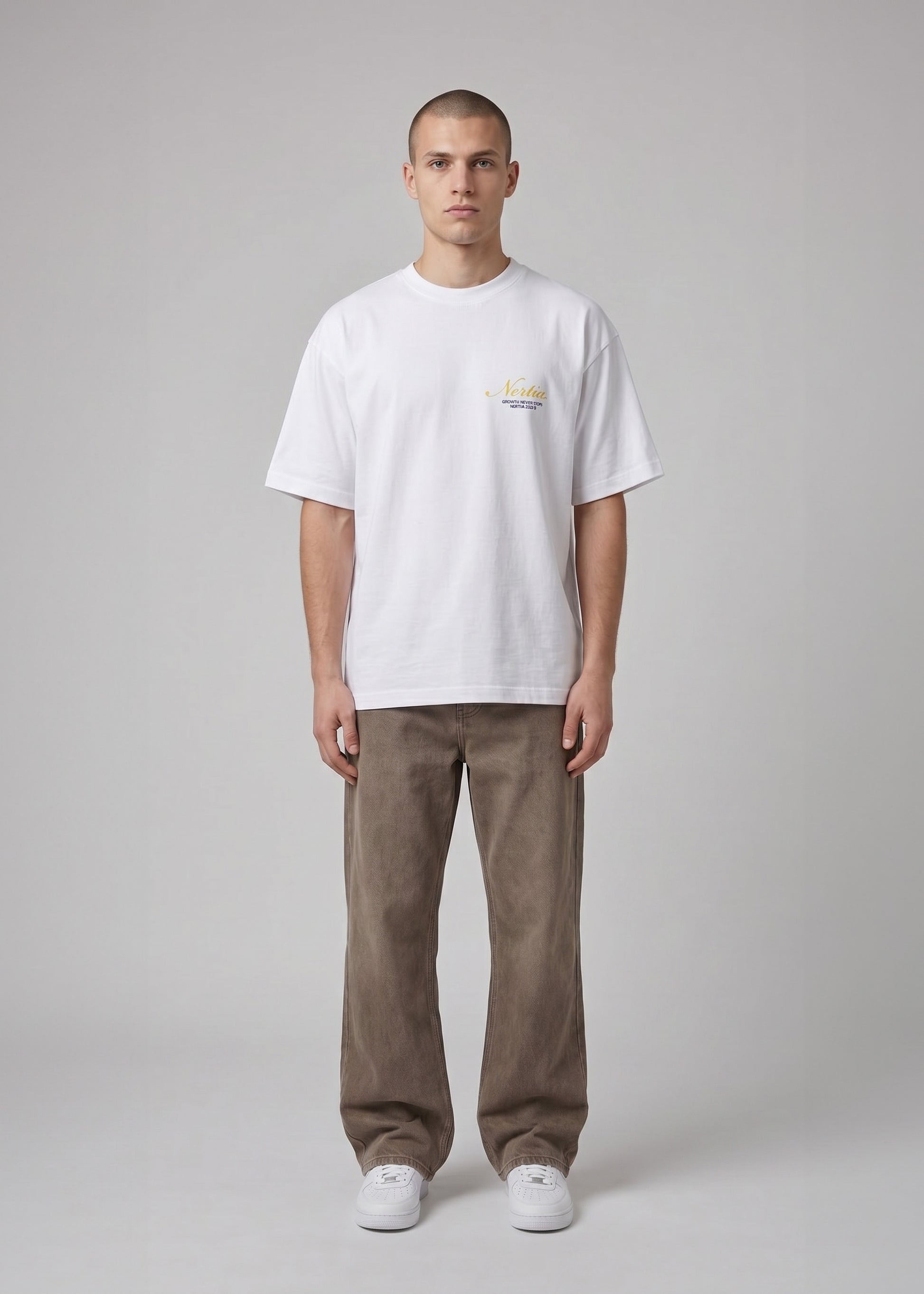 Man wearing a white t-shirt with a small logo and brown pants on a gray background