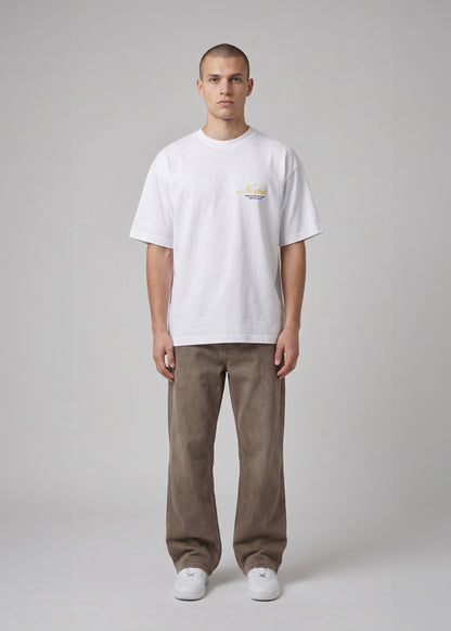 Man wearing a white t-shirt with a small logo and brown pants on a gray background