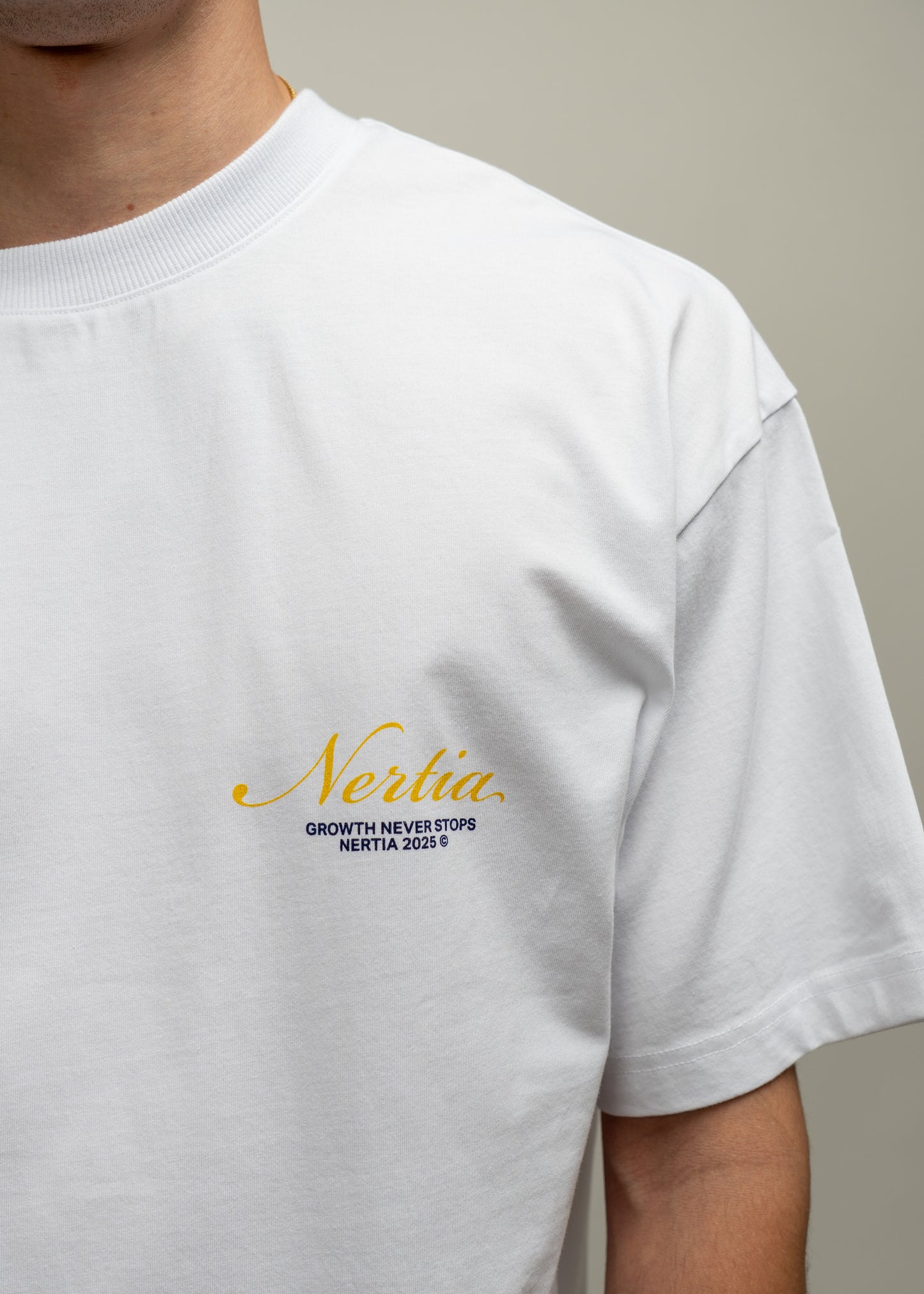 White t-shirt with gold and black text on a neutral background
