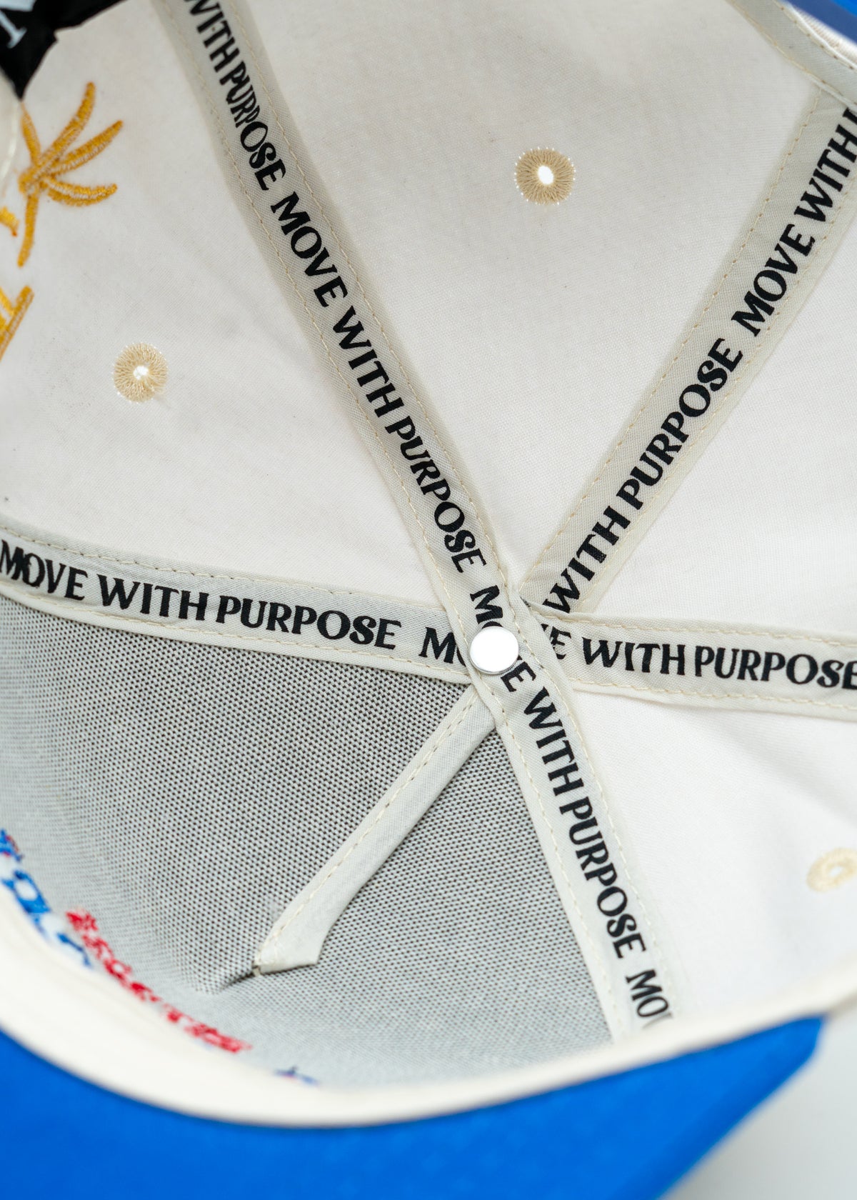 Close-up of the interior of a baseball cap showing white adjustable straps printed with 'MOVE WITH PURPOSE' in black, a white crown, and a blue brim visible at the bottom edge.