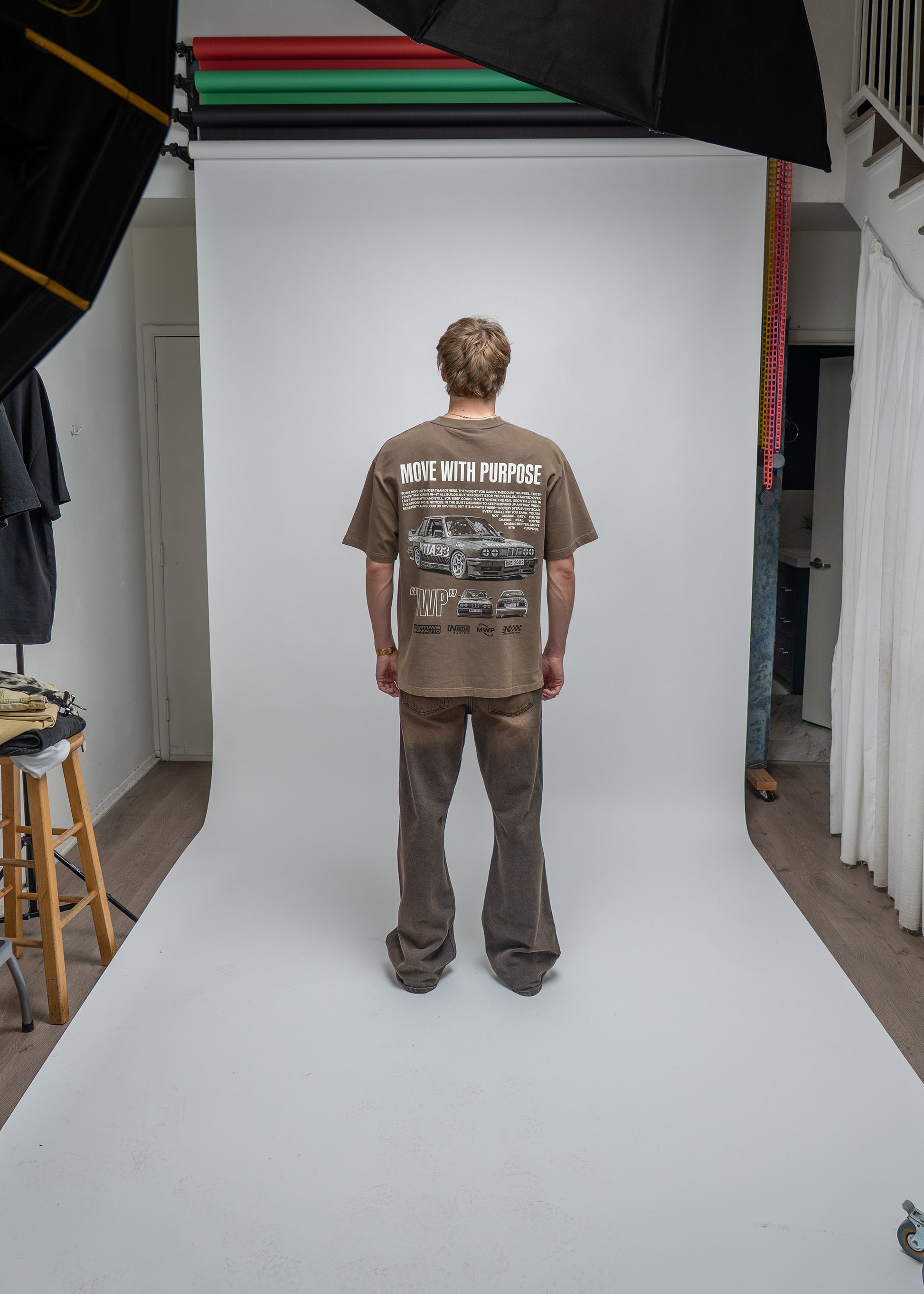 Person wearing a t-shirt with graphic design on a white backdrop in a studio setting